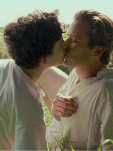 Elio and Oliver kiss while lying in the grass.
