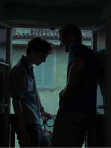 Elio and Oliver's silhouettes. They stand in front of each other, framed by an open window.