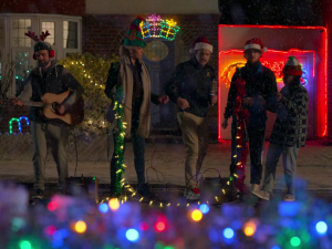 Hannah Waddingham and Jason Sudeikis as Rebecca Welton and Ted Lasso with some street performers on Ted Lasso Carol of the Bells